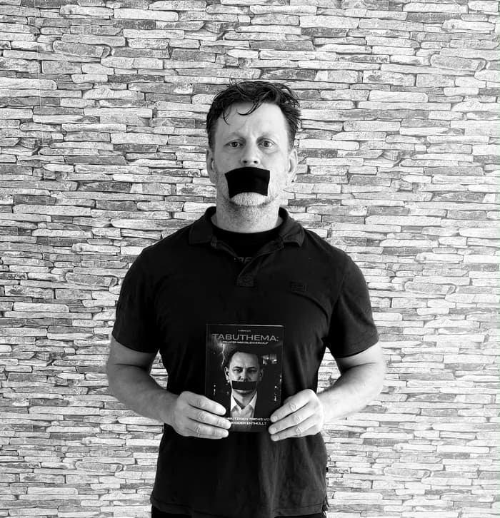 Partner von Markus Kehl mit dem Buch vor einer Steinwand