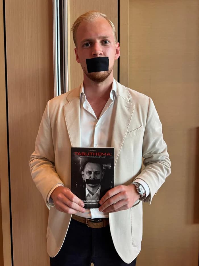 Kollege von Markus Kehl im hellen Sakko mit dem Buch