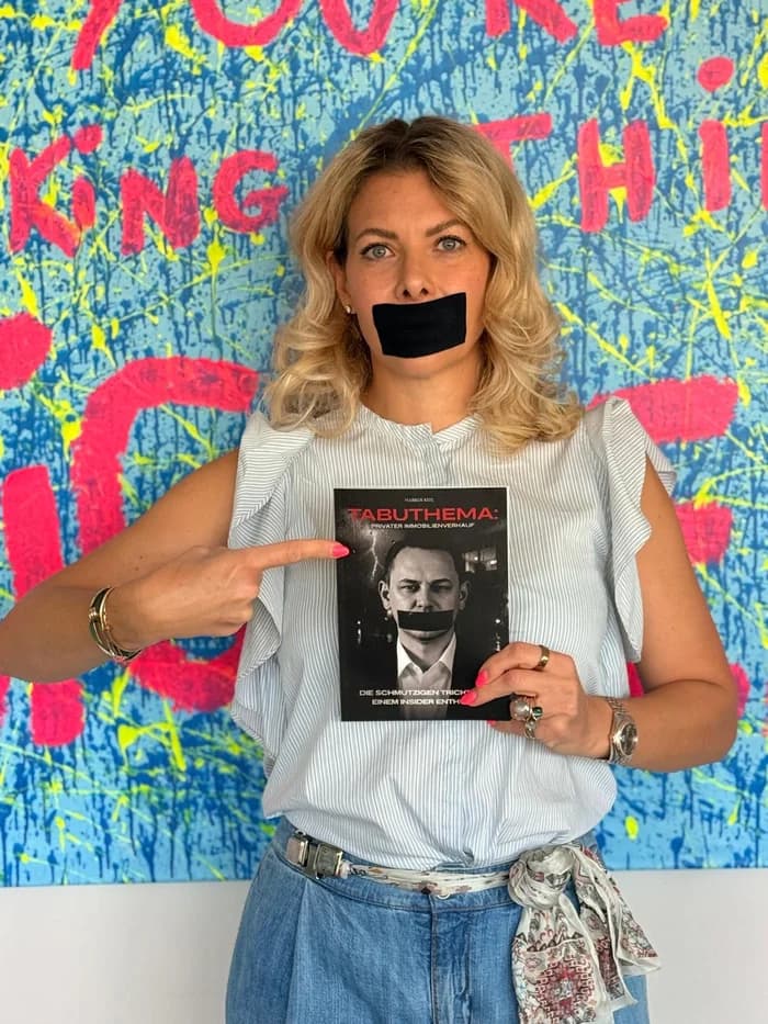 Partnerin von Markus Kehl mit dem Buch vor einem Kunstwerk